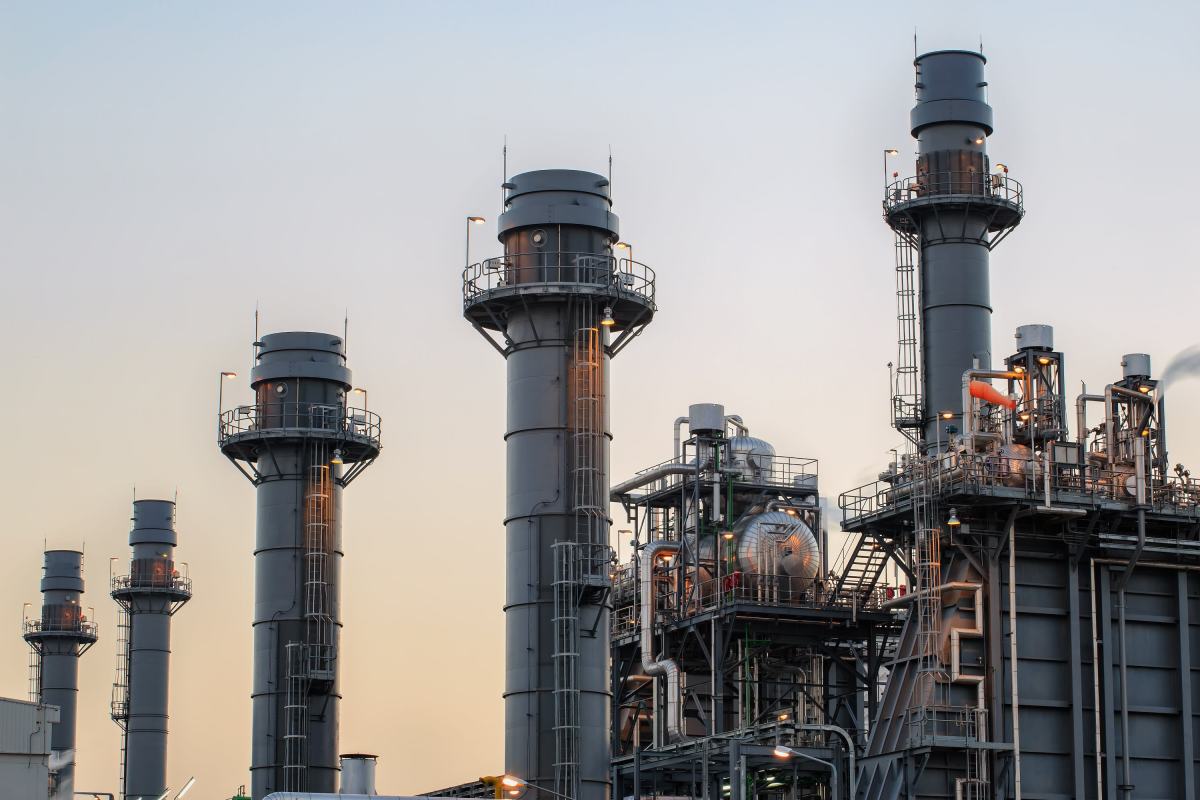 Natural-gas power plant smoke stacks against a twilight sky in the report on Amazon's planned Texas data center