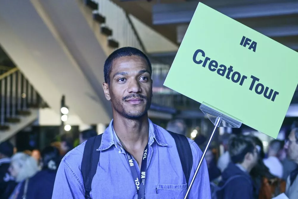 IFA creator-tour participant holding a green Creator Tour sign in the exhibition hall